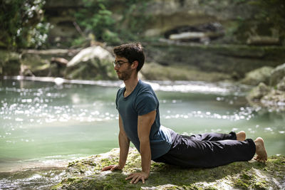 Side view of young man exercising in river