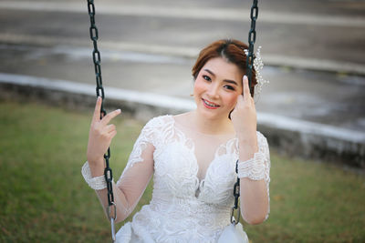 Portrait of smiling young bride sitting on swing