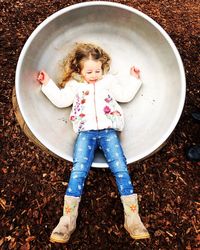 Directly above shot of girl lying down in container on table