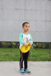 Portrait of boy holding plastic disc on footpath at park