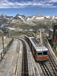 Train on railroad track by mountain against sky