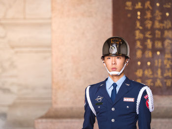 Portrait of young man standing against wall