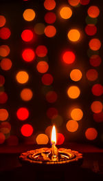 Close-up of illuminated diya against lights