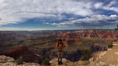 Woman standing on landscape against cloudy sky