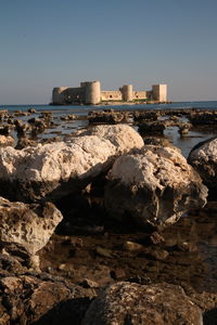 Rocks by sea against clear sky