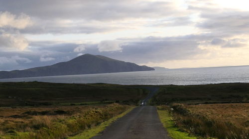 Scenic view of road by sea against sky