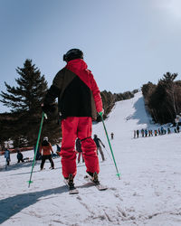 Rear view of person skiing on snow covered field against sky