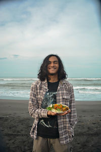 Man with food in hand on the beach