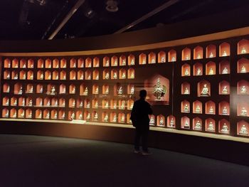 Rear view of woman standing in illuminated building