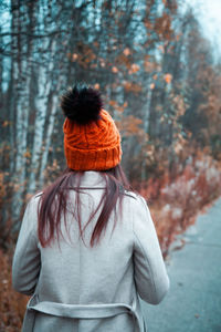 Rear view of woman standing by tree in forest