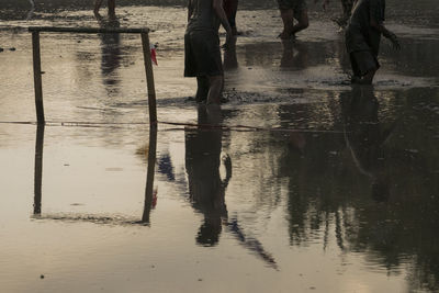 Low section of people standing on wet road during rainy season