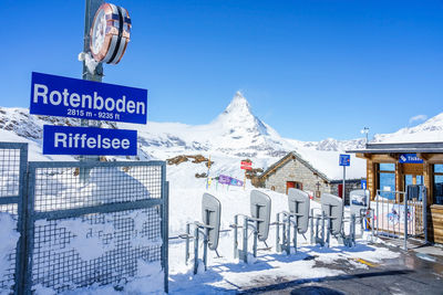 Information sign on snowcapped mountains against blue sky