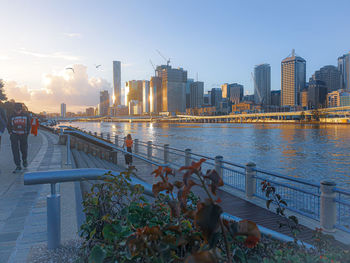 Bridge over river by buildings against sky in city