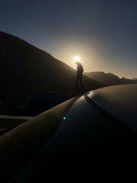 Silhouette person standing on mountain against sky during sunset