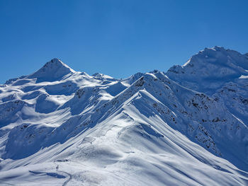 Scenic view of snowcapped mountains against clear blue sky