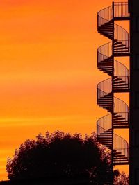 Low angle view of silhouette trees against orange sky