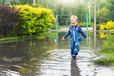 Full length of boy walking in puddle