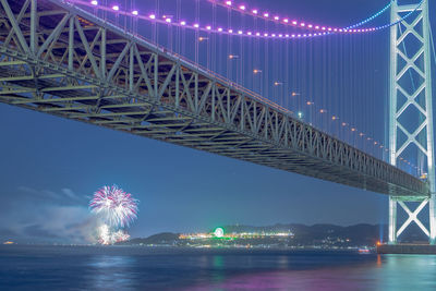 Low angle view of illuminated bridge over river at night