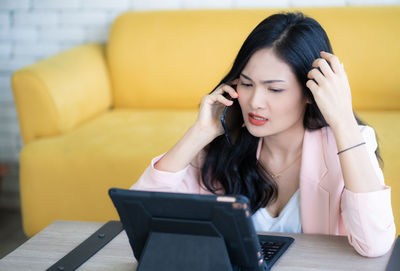 Young woman using mobile phone while sitting on sofa