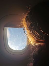 Close-up of woman looking through airplane window