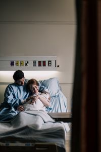 Rear view of couple sitting on bed