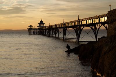 Silhouette of bridge over sea during sunset