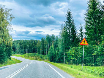 Road amidst trees and plants against sky