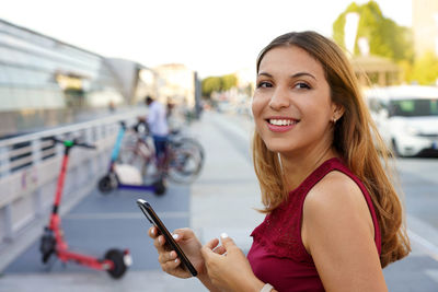 Smiling young woman using mobile phone outdoors
