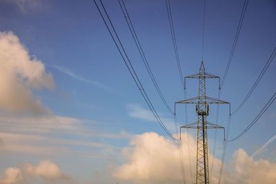 Low angle view of electricity pylon against blue sky