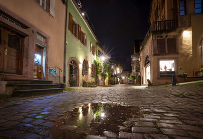 Illuminated street amidst buildings in city at night