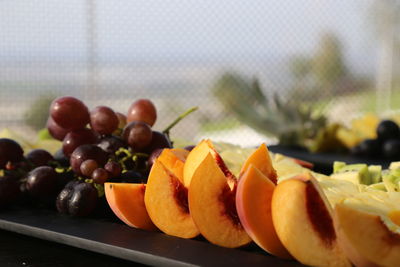 Close-up of peaches and grapes in plate on table