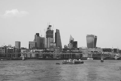 Modern buildings by river in city against sky