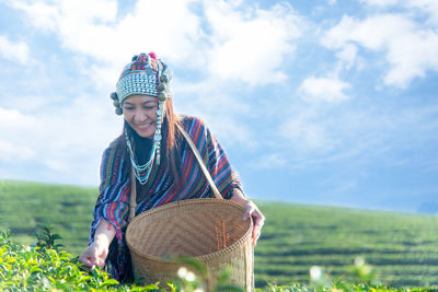 Woman harvesting tea crops against sky