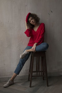 Portrait of woman sitting on chair against wall