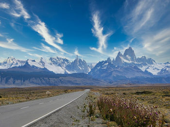 Road by snowcapped mountains against sky