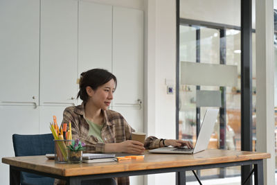 Woman using laptop while sitting on table