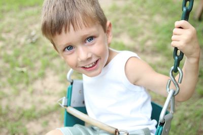 Portrait of smiling boy swinging at playground