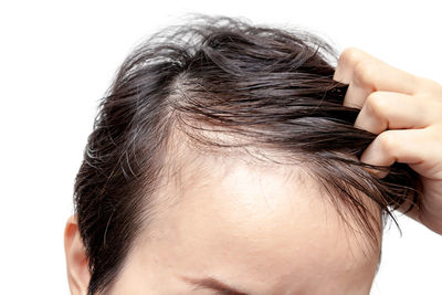 Close-up of man with hand in hair against white background