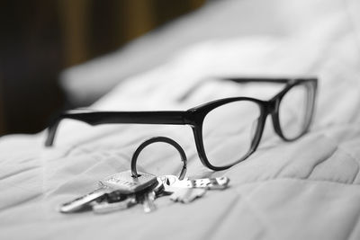 Close-up of eyeglasses and house key on bed