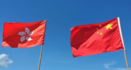 Low angle view of red flags against blue sky