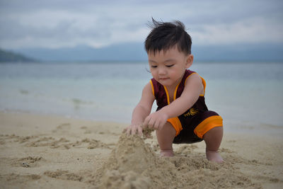Boy playing on beach against sky