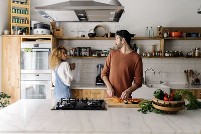 Rear view of man and woman standing in kitchen at home