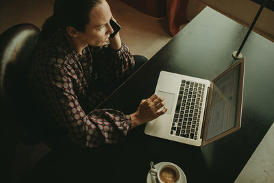 Businesswoman talking on phone while working in office