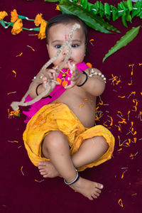 Cute indian boy dresses as lord rama with bow and flowers from top angle