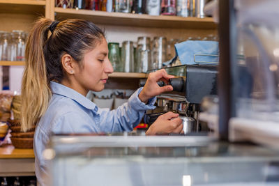 Side view of young woman using mobile phone in cafe