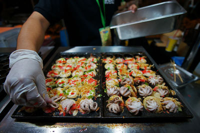 Midsection of person preparing food on barbecue grill