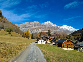 Road amidst buildings and mountains against sky