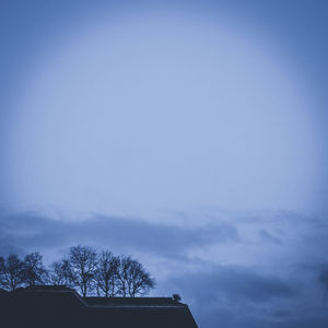 Low angle view of silhouette trees against blue sky