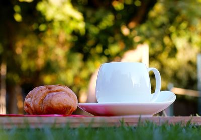 Close-up of croissant and tea cup on cutting board