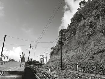 Railroad tracks by road against sky on sunny day